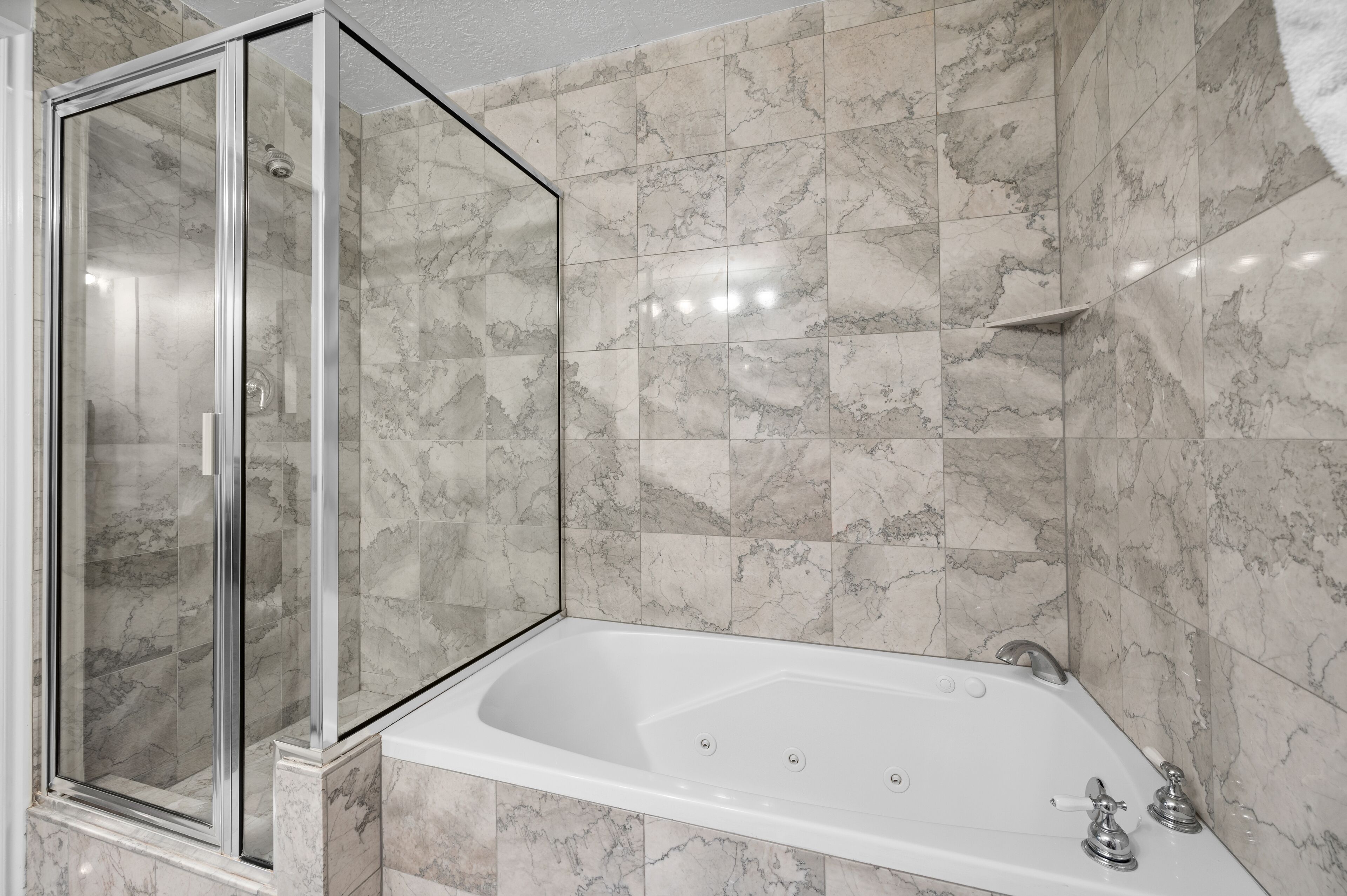 Un bagno moderno con cabina doccia in vetro, vasca da bagno indipendente e piastrelle in marmo.