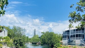 Une rivière avec un quai, bordée de verdure et entourée de bâtiments.