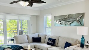 Un salon moderne avec un canapé d’angle, une table basse, une lampe et un ventilateur de plafond.