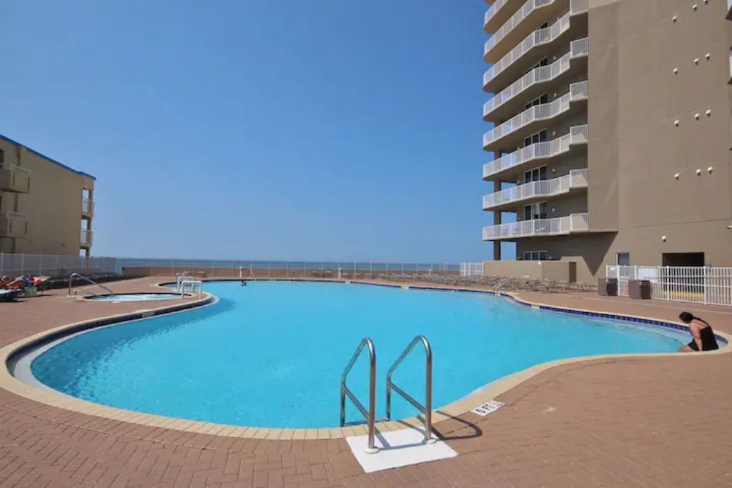 A swimming pool with a curved edge, surrounded by a brick deck.