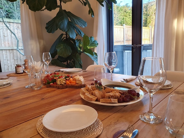 A dining table set with plates of food, wine glasses, and cutlery.