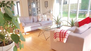 Un salón con un sofá, una mesa de centro de vidrio y una planta en maceta.