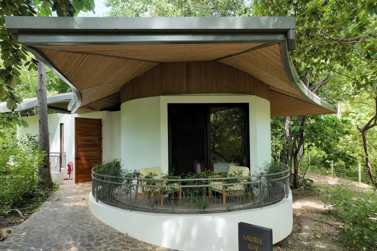 A modern building with a curved entrance, a covered porch, and a sign indicating a 'Laurel Suite'.