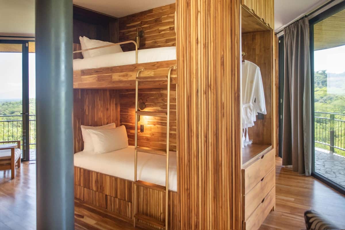 A bunk bed room with wooden walls and a balcony with a view.