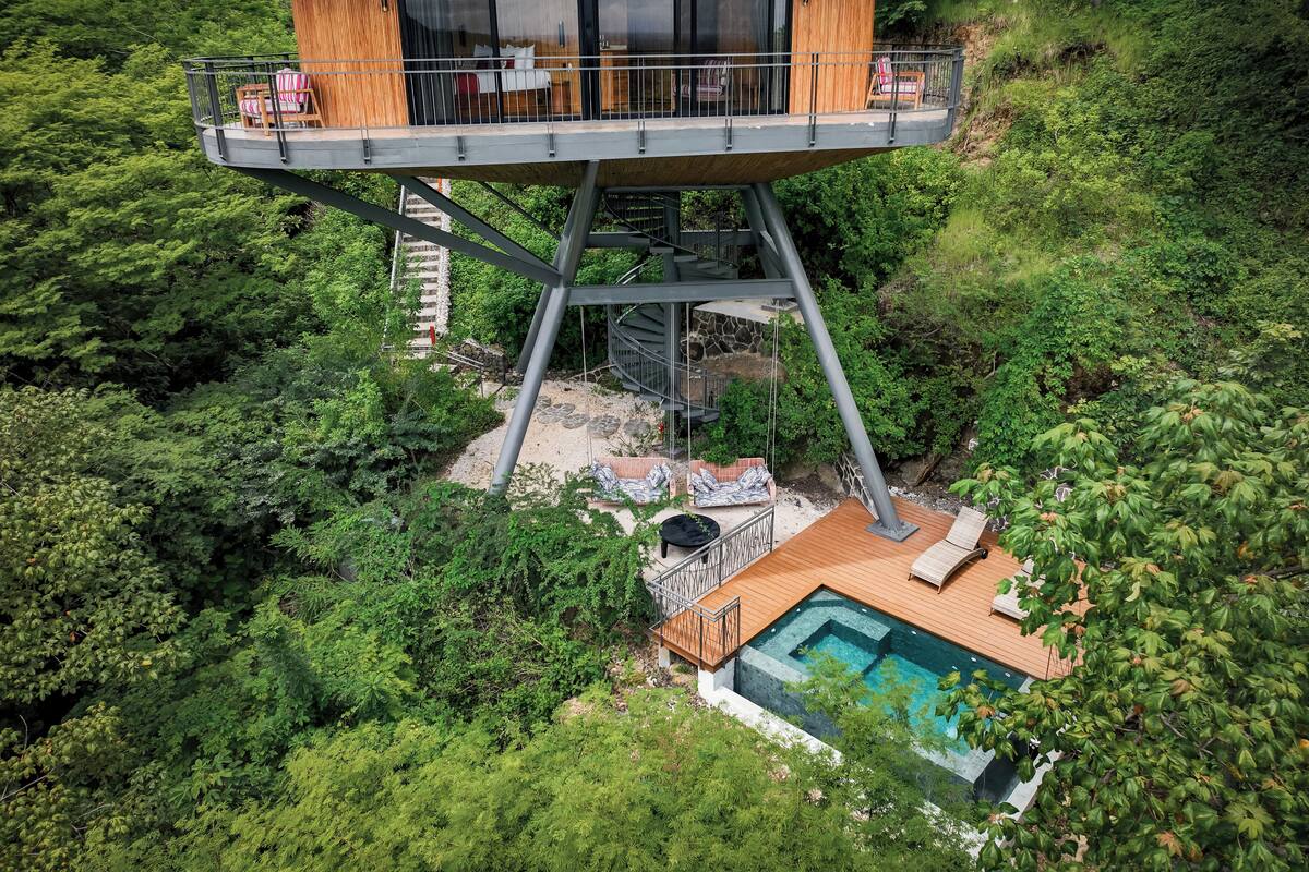 A high-rise treehouse with a balcony, a pool, and a staircase leading to the upper level.