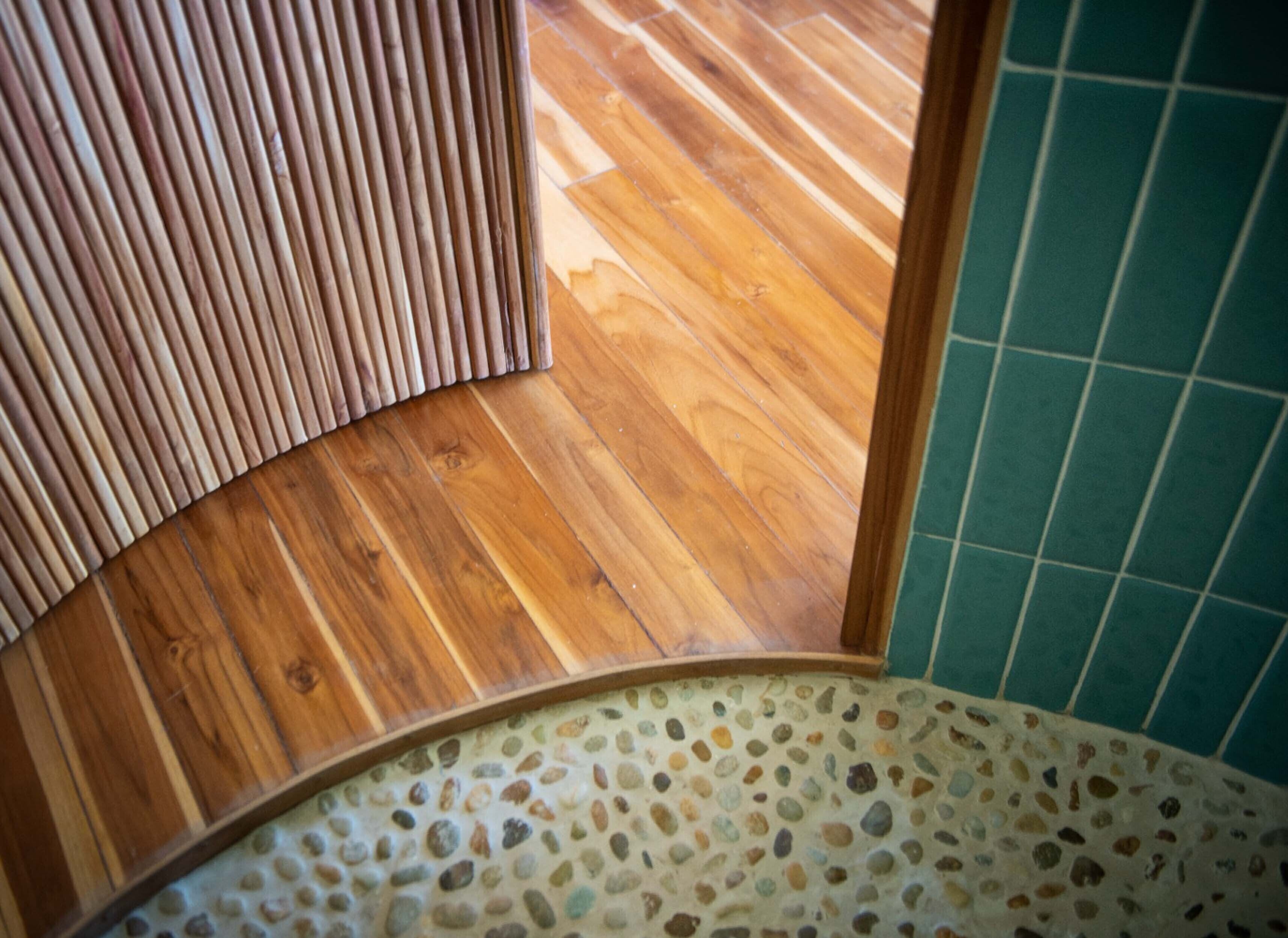 A wooden floor with a curved wooden panel and a tiled wall.