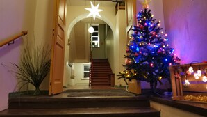 A staircase leading to a landing with a Christmas tree adorned with colorful lights and a star on top.