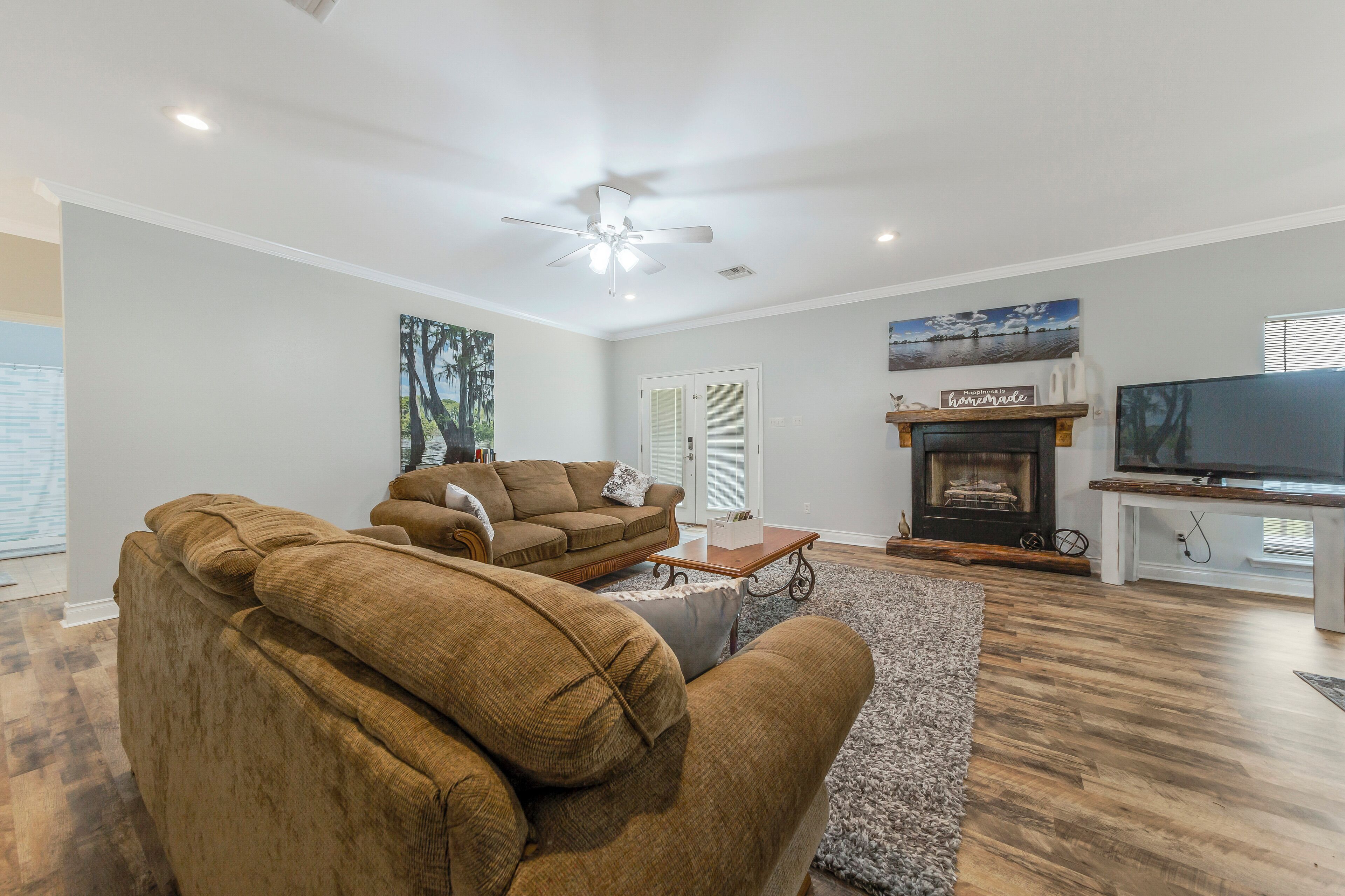 A living room with two brown couches, a fireplace, a television, and a ceiling fan.