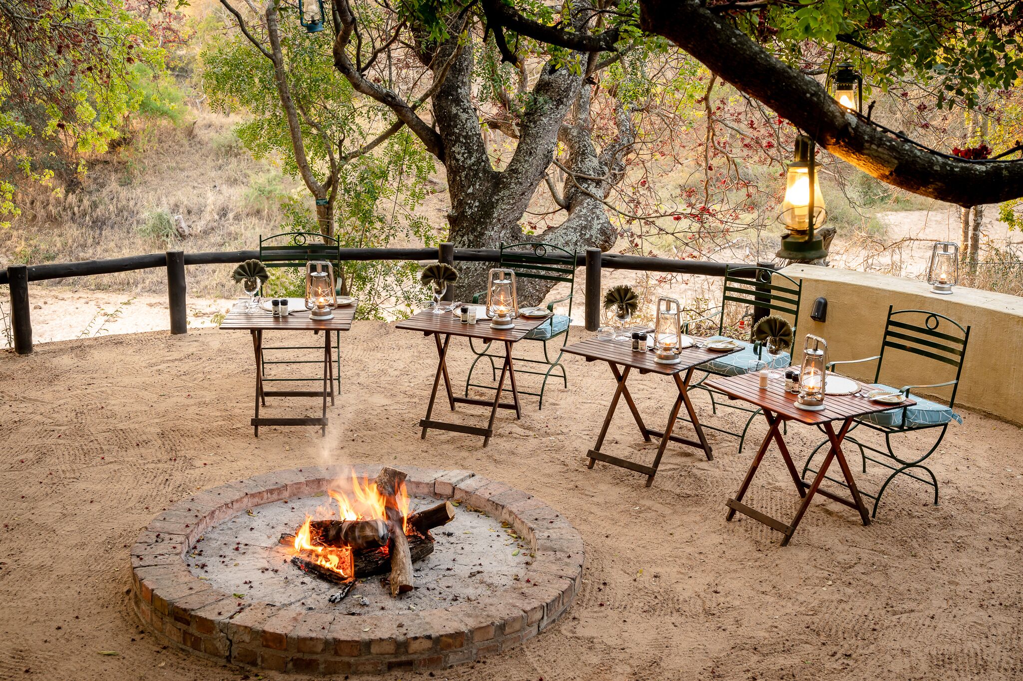 An outdoor dining area with tables and chairs, a fire pit, and a view of the surrounding landscape.