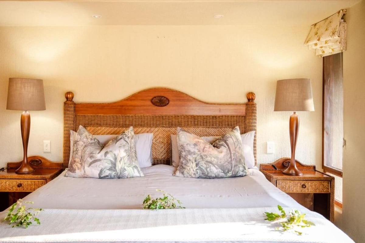 A neatly made bed with floral pillows, two bedside lamps, and a wooden headboard.