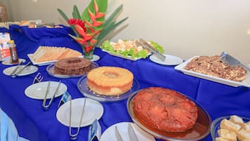 Un tavolo per buffet con diversi piatti, tra cui torte, pasticcini e un'insalata di frutta.