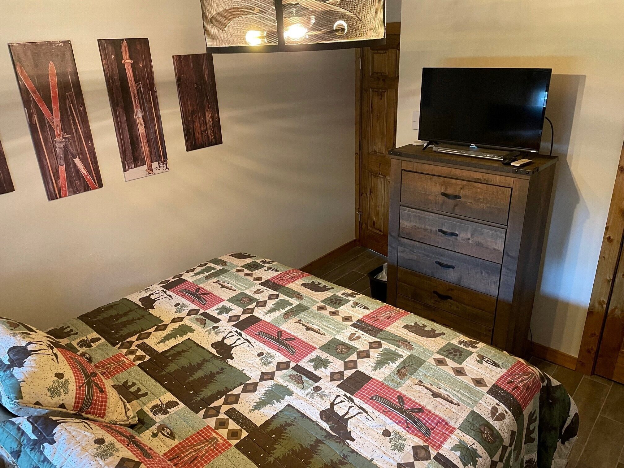 Un dormitorio con una cama, un aparador de madera, un televisor y decoración en la pared.