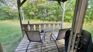 A covered outdoor deck with two chairs and a table, surrounded by a wooden railing and a grassy lawn. - Clean, Cozy & Completely Updated! 1B 1B Condo w Jetted Tub Room! (Wakefield)