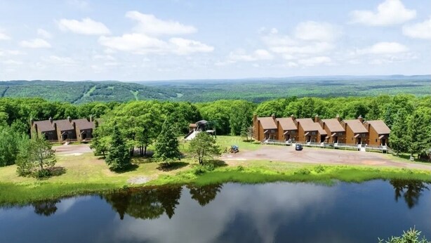 A lakeside lodge with multiple cabins, a small dock, and a clear view of the surrounding forest. - Clean, Cozy & Completely Updated! 1B 1B Condo w Jetted Tub Room! (Wakefield)
