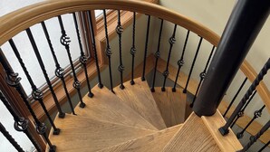 Eine Wendeltreppe aus Holz mit schwarzen Geländern und einem Glaseinschluss.