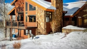 Ein modernes mehrgeschossiges Haus mit Natursteinfassade, großen Fenstern und einem Balkon.