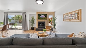 A modern living room with a fireplace, a dining area, and a view of the outdoors.