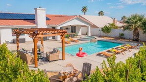 A backyard with a swimming pool, outdoor furniture, and a pergola.
