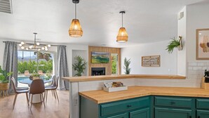 A modern kitchen with a wooden countertop, teal cabinets, and pendant lights.
