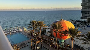 A pool area with lounge chairs and a large, colorful dome structure. - Modern Beachfront Condo with Stunning Ocean View (Hollywood)
