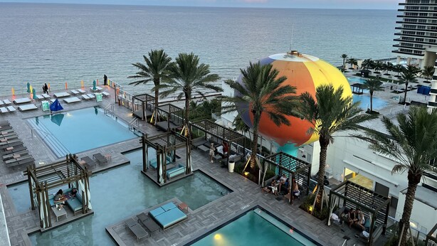 A rooftop pool area with multiple pools, lounge chairs, and a large colorful dome structure. - Modern Beachfront Condo with Stunning Ocean View (Hollywood)
