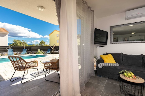A living area with a pool, outdoor furniture, a sofa, a TV, and a mirror. - Apartment PATRICK with private pool (Čižići)