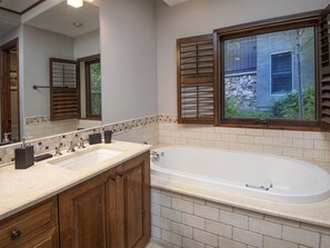 A bathroom with a double sink vanity, a freestanding bathtub, and a large mirror. - Cascade Village Condo (Vail)