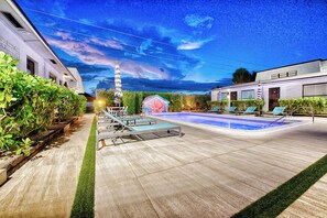 Ein Poolbereich mit Liegestühlen und einer kleinen Holzterrasse.