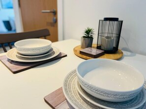 A dining table with stacked plates and a candle holder. - Cosy Studio Apartment - Chavasse Apartments (Liverpool)
