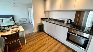 Eine moderne Küche mit weißen Schränken, einer Edelstahl-Dunstabzugshaube und einem Holzespeisetisch mit Stühlen.