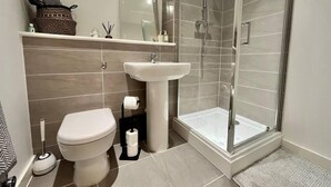 Ein modernes Badezimmer mit Toilette, Waschbecken und einer Duschkabine.