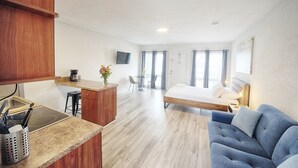 A compact hotel room with a kitchenette, a bed, a sofa, and a dining area. - Open-Concept Studio #202 | Airy Layout Sleeps 3 (Deerfield Beach)