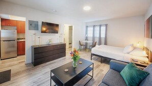 Ein modernes Hotelzimmer mit einer Küchenzeile, einem Essbereich, einem Bett und einem Wohnbereich.