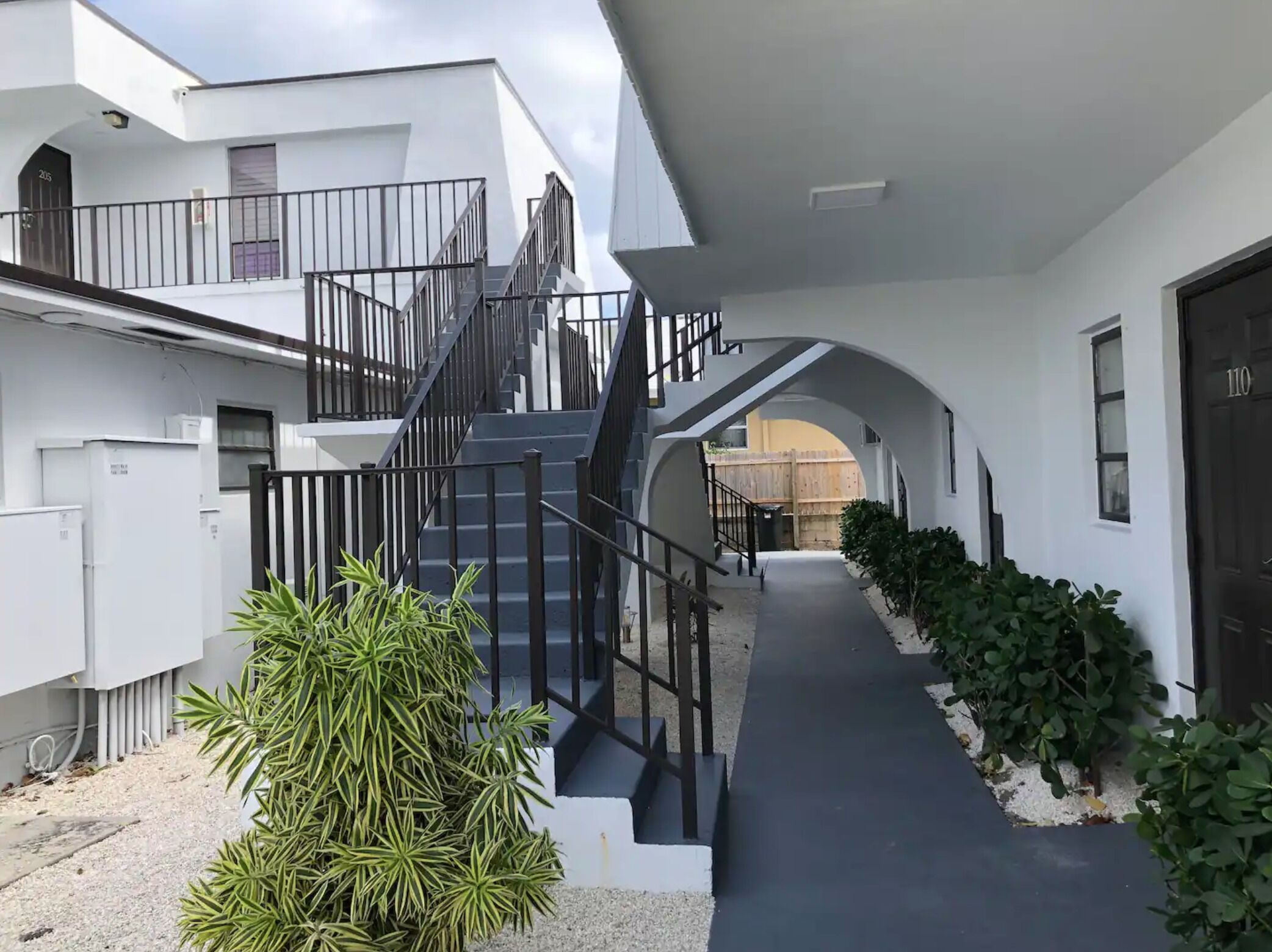 Un edificio moderno con una scalinata centrale, una passerella coperta e un ingresso con cancello.