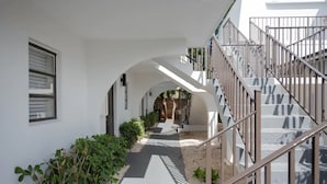 A covered walkway with a staircase on the right, leading to an upper level. - Largest Studio at Pier Walk • Pets OK (Deerfield Beach)