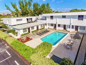 A modern hotel with a rooftop pool, sun loungers, and a well-maintained garden.