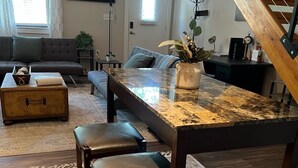 Un coin repas avec une table et des chaises en bois, une plante en pot et un escalier.