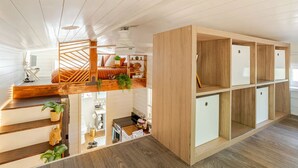 A modern interior with a wooden staircase, a loft bedroom, and built-in storage units. - Tiny home 🏡 Northgate- 15min to downtown (Seattle)