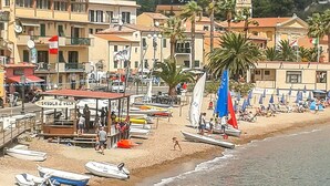 A coastal town with a beach, boats, and a school named "SCUOLA & VELATA".