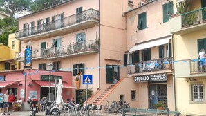 A multi-story building with balconies, a beach bar, and a shop named 'SCOGLIO VIAGGI & TURISMO'.