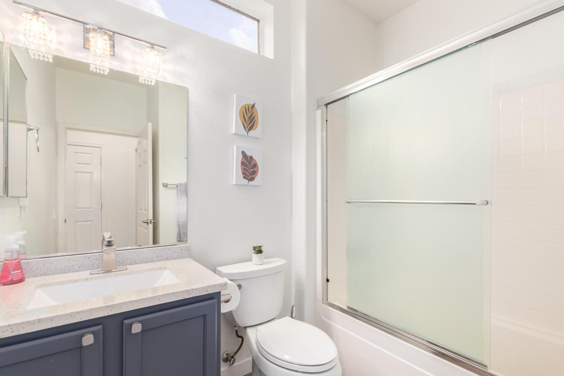 A bathroom with a large mirror, a toilet, a sink, and a glass shower enclosure.