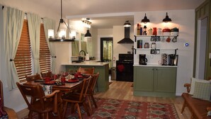 Un comedor con una mesa y sillas de madera, una cocina con estufa y armarios, y una alfombra estampada en el suelo.