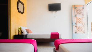 Quarto com duas camas, televisão na parede e um portão de metal decorativo.