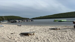 A sandy beach with boats docked in the background and a green inflatable on the water. - Beautiful, Cozy, All-Seasons Mountain/Lake Townhome (Lake Harmony)