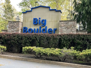 A sign with "Big Boulder" written in blue letters on a beige background, flanked by stone pillars and surrounded by greenery. - Beautiful, Cozy, All-Seasons Mountain/Lake Townhome (Lake Harmony)