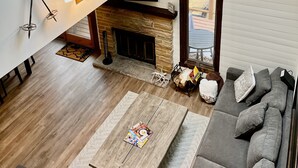 A modern living room with a fireplace, a sofa, a coffee table, and a skylight. - Beautiful, Cozy, All-Seasons Mountain/Lake Townhome (Lake Harmony)