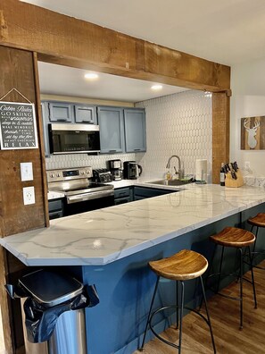 A modern kitchen with a large island, bar stools, and a chalkboard with kitchen tips. - Beautiful, Cozy, All-Seasons Mountain/Lake Townhome (Lake Harmony)