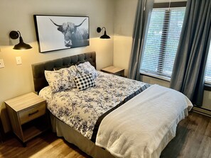A neatly made bed with floral bedding, a framed picture above it, and a window with curtains. - Beautiful, Cozy, All-Seasons Mountain/Lake Townhome (Lake Harmony)
