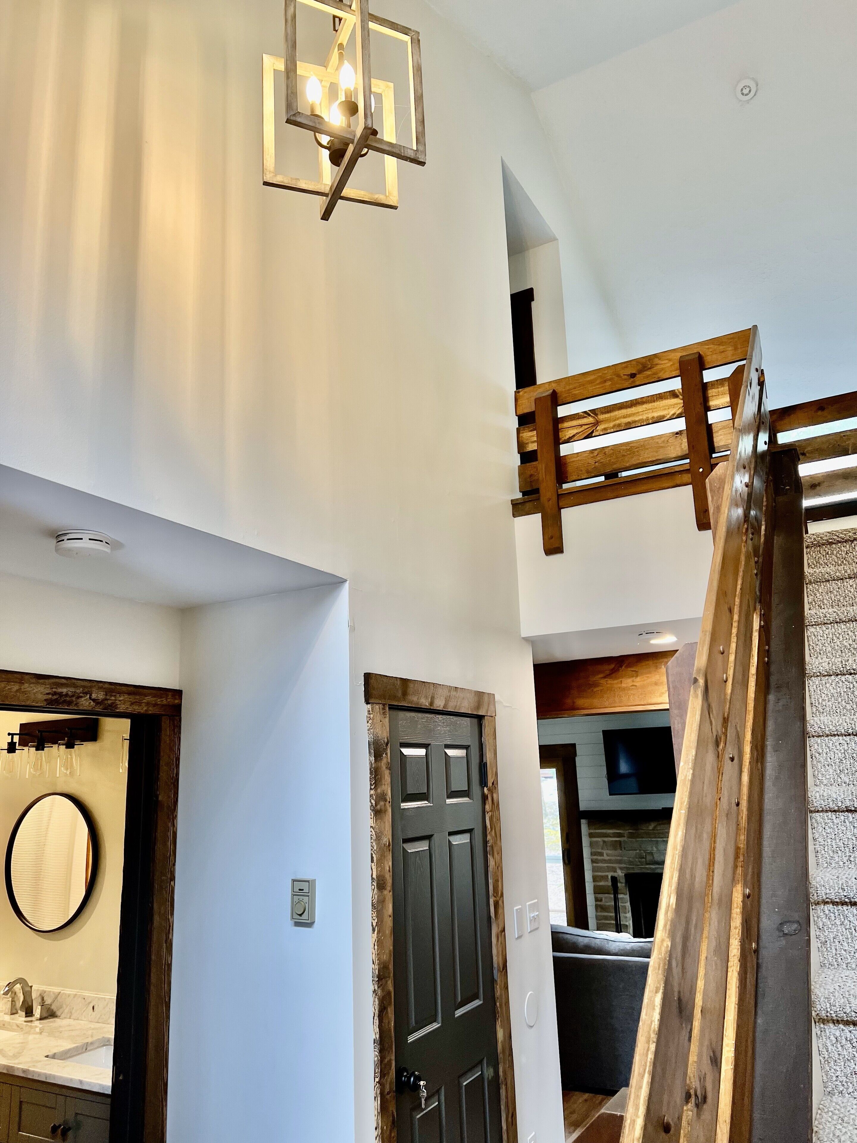 Um interior moderno com escada, porta de madeira e banheiro com espelho e pia.