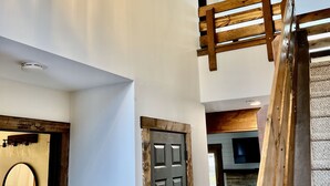 A modern interior with a staircase, a wooden door, and a bathroom with a mirror and sink. - Beautiful, Cozy, All-Seasons Mountain/Lake Townhome (Lake Harmony)